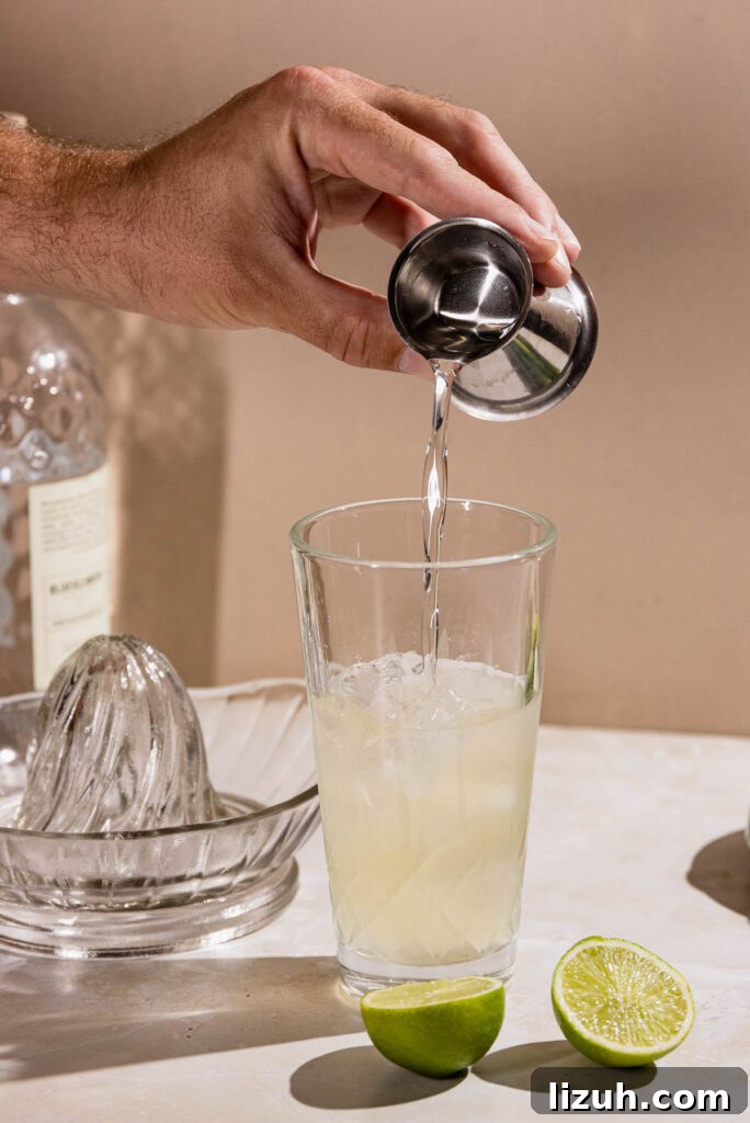 Classic Gimlet Cocktail Recipe: How to Make the Perfect Gimlet 6 Hand pouring simple syrup into a cocktail shaker.