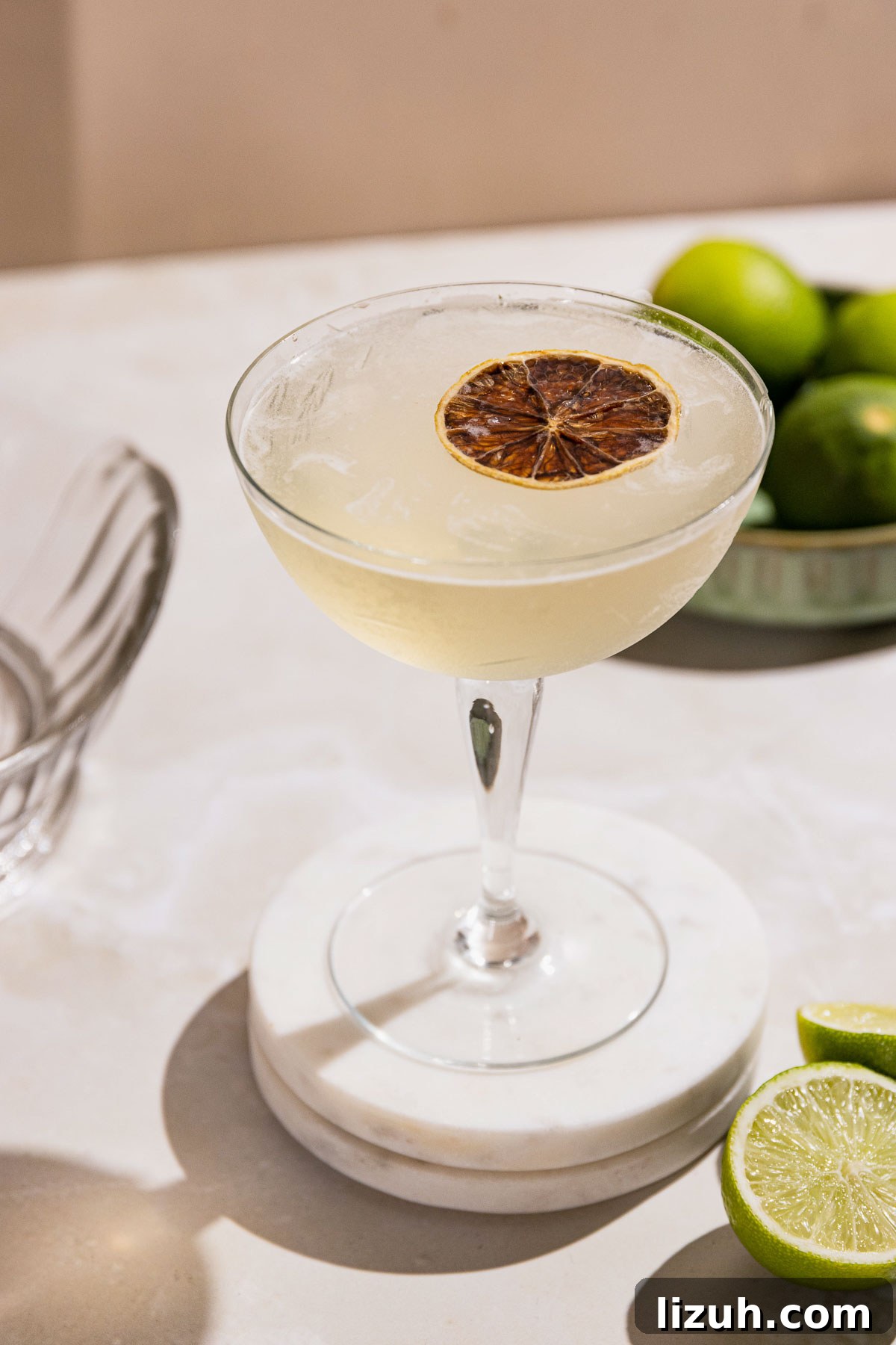 Classic Gimlet Cocktail Recipe: How to Make the Perfect Gimlet 10 Frosty gimlet cocktail in a coupe glass on a table with fresh limes.