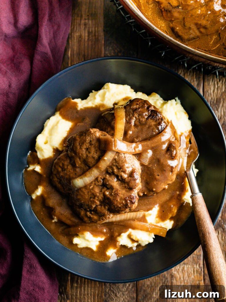 plate of hamburger steaks with onion gravy over a bed of mashed potatoes