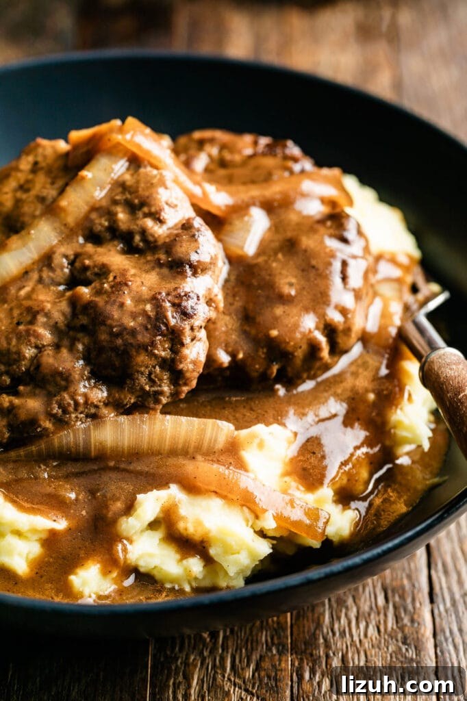 plate of hamburger steaks with onion gravy over a bed of mashed potatoes