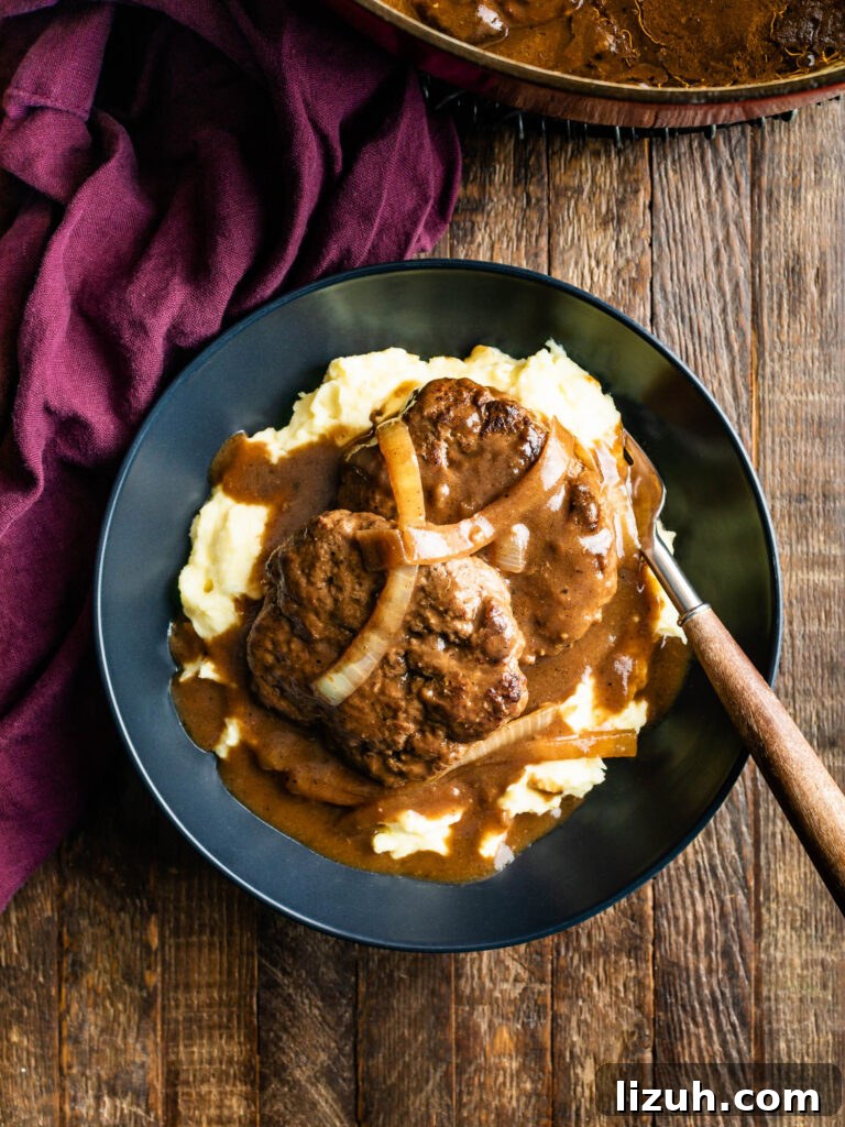 plate of hamburger steaks with onion gravy over a bed of mashed potatoes