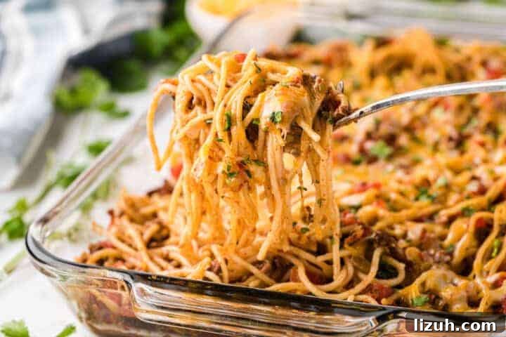 Taco Spaghetti being served out of a glass casserole dish.