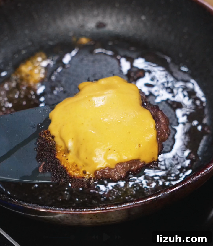 How to Make a Juicy Smash Burger at Home 6 Cheddar cheese melted over flipped smash patties in a pan, locking in flavor and creating the gooey layer for the Asian Smash Burger.