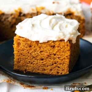 A slice of easy pumpkin cake served on a plate with lots of frosting