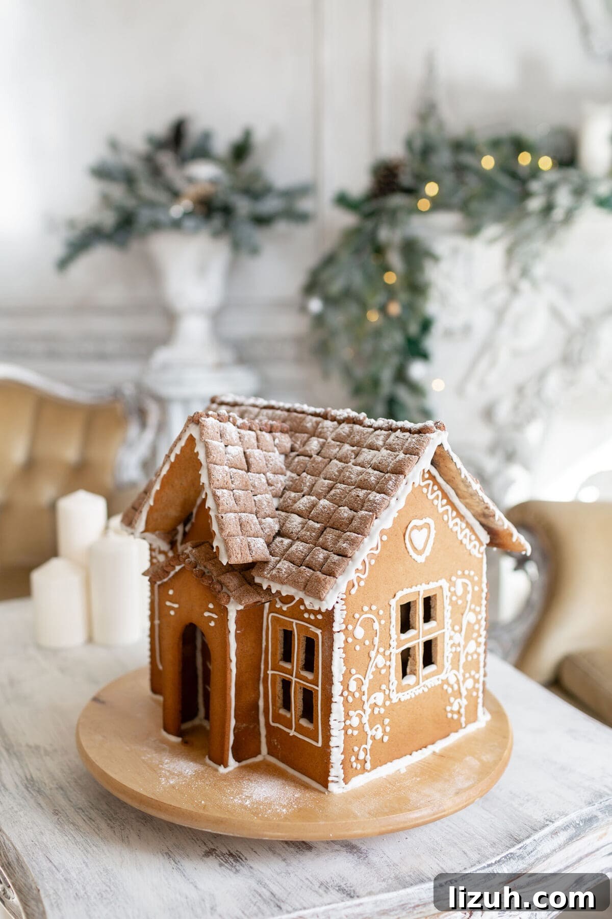 Host a Festive Gingerbread House Party: Tips, Themes & Checklist 7 a decorated gingerbread house sits on a table in front of a tree and lit garland in a bright room