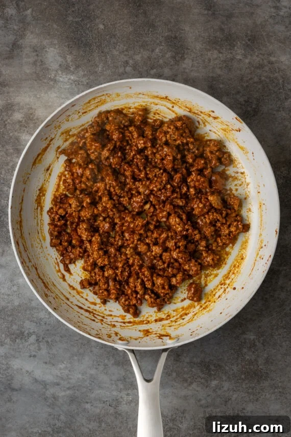 Cooked seasoned ground beef in a skillet.