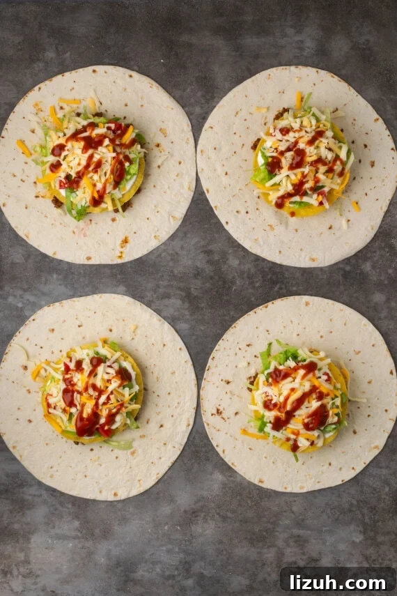 Overhead view of four assembled crunch wraps topped with meat, corn tortillas, veggies, and cheese.