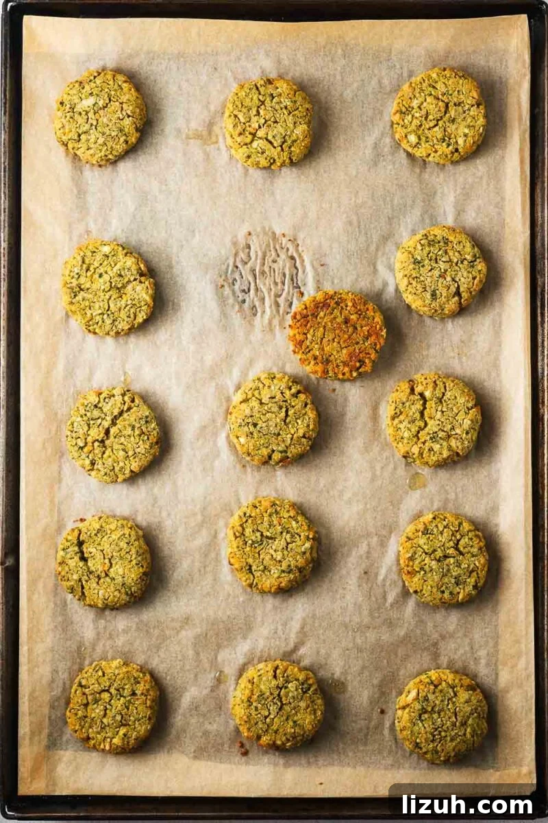 Crispy Oven-Baked Falafel Using Canned Chickpeas 10 A baking sheet with baked falafel and one falafel flipped over to reveal a golden brown bottom.