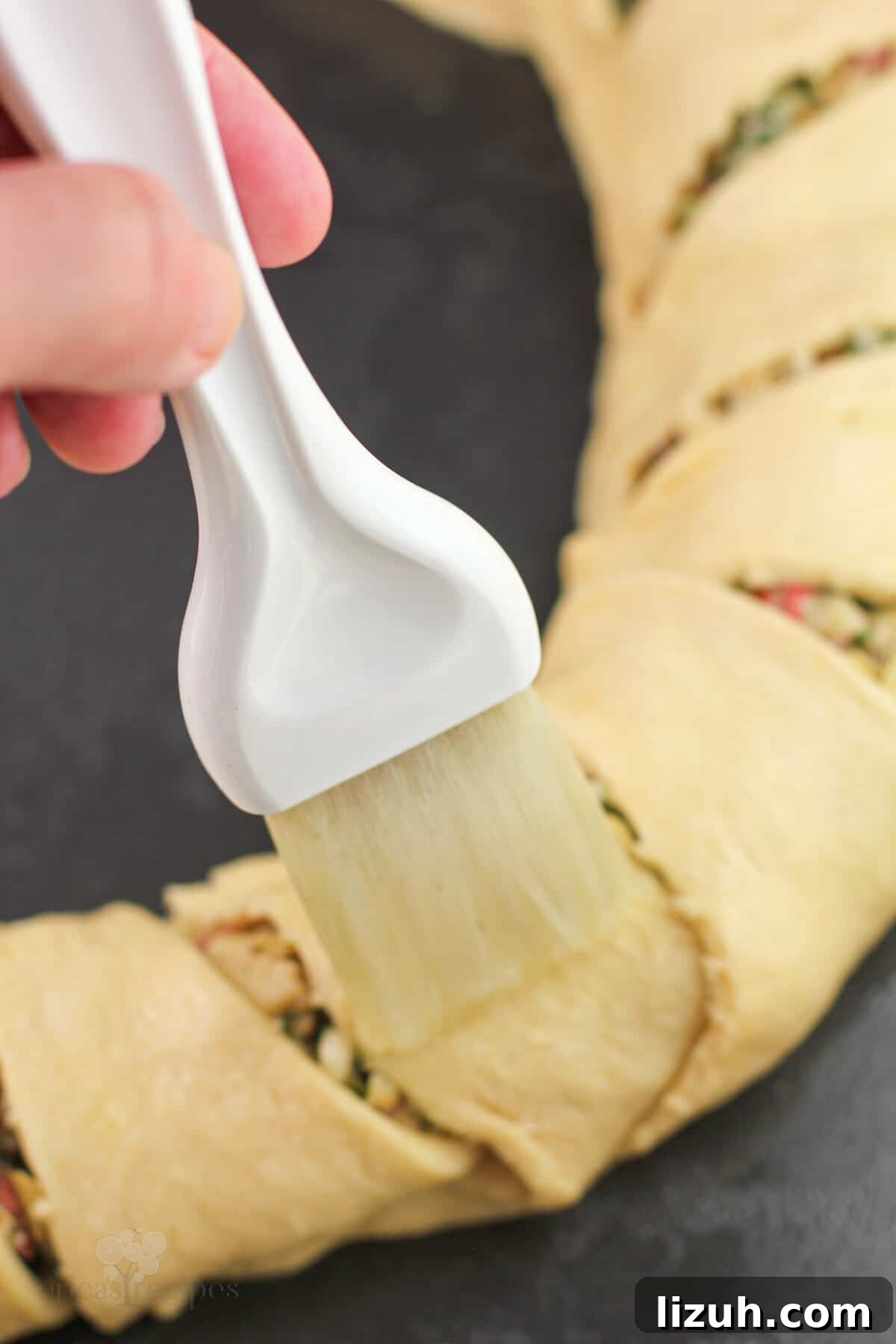 pastry brush brushing egg white on dough