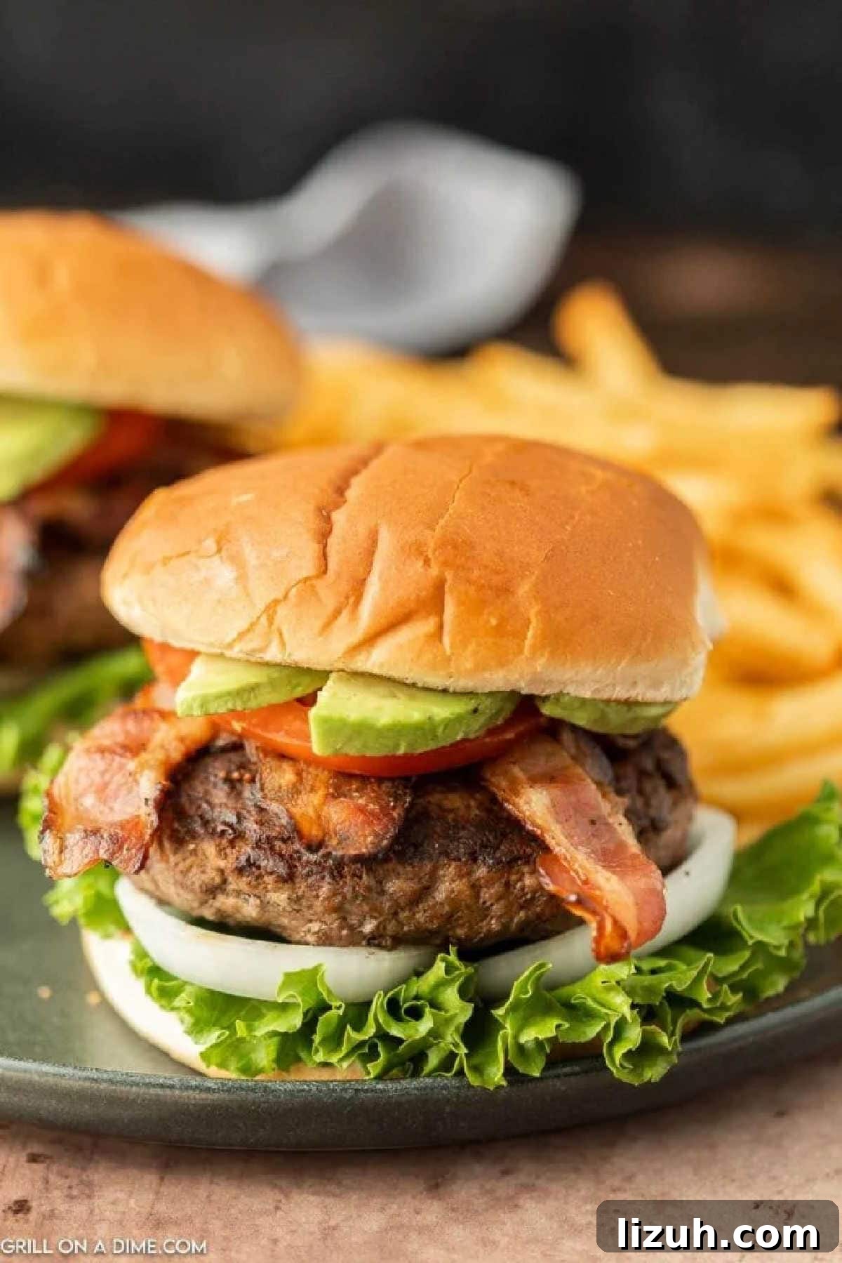 Hamburger topped with slice avocado, tomato, bacon and slice onions and lettuce