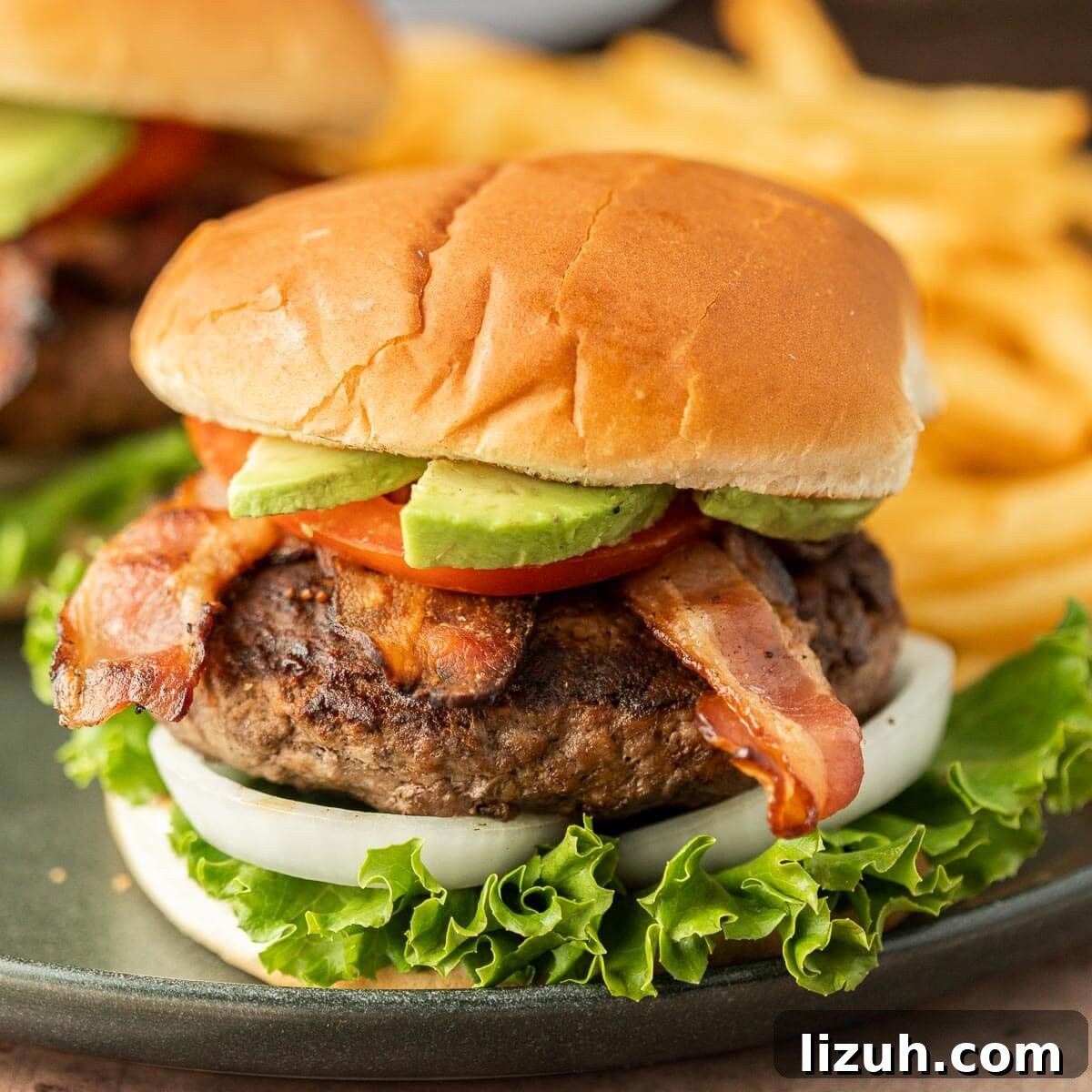Avocado Bacon Burger on a plate with a side of french fries