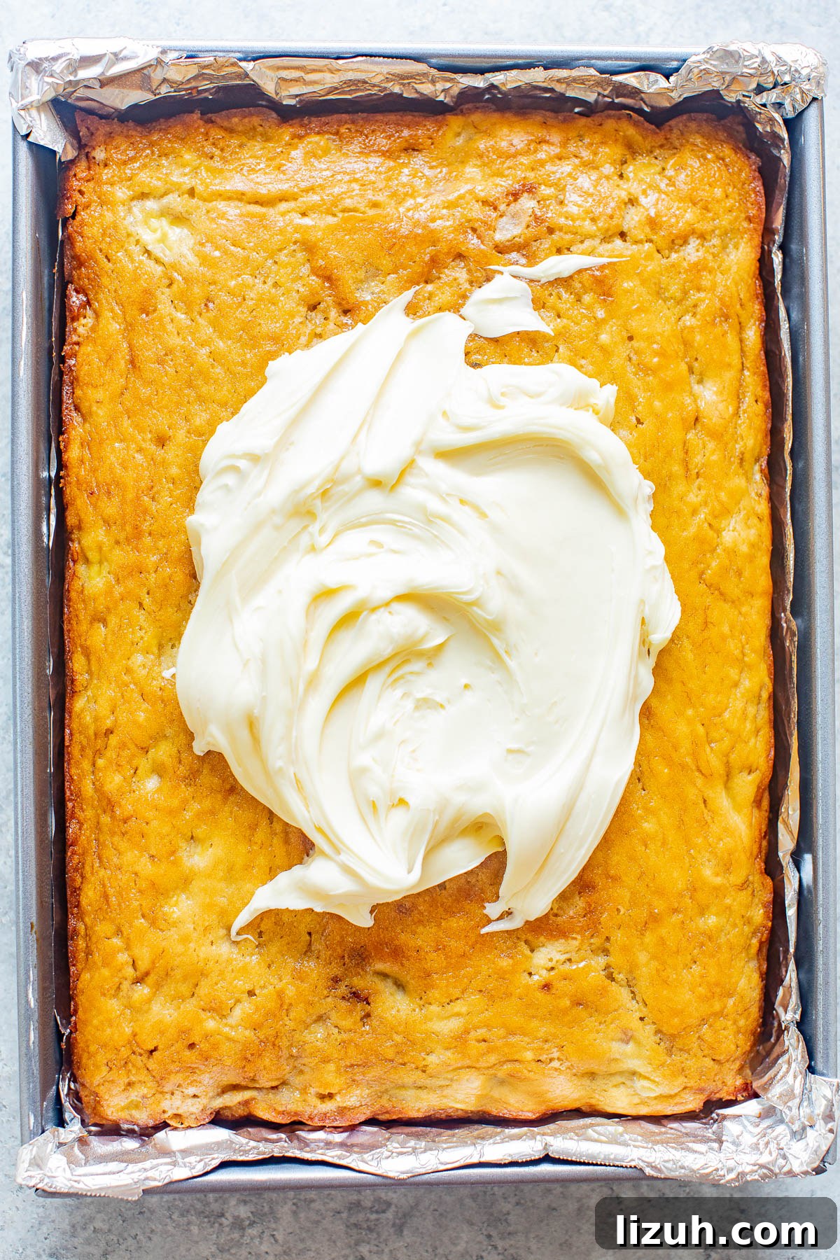Cream cheese frosting dolloped into the center of a banana cake. 