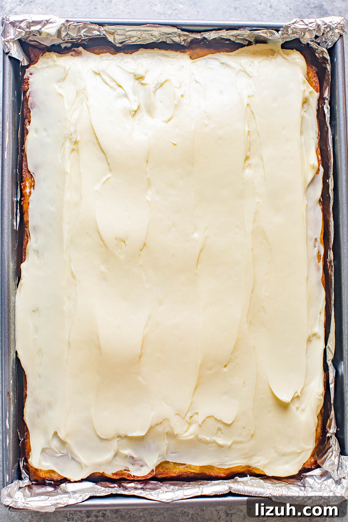 A banana cake topped with cream cheese frosting. 