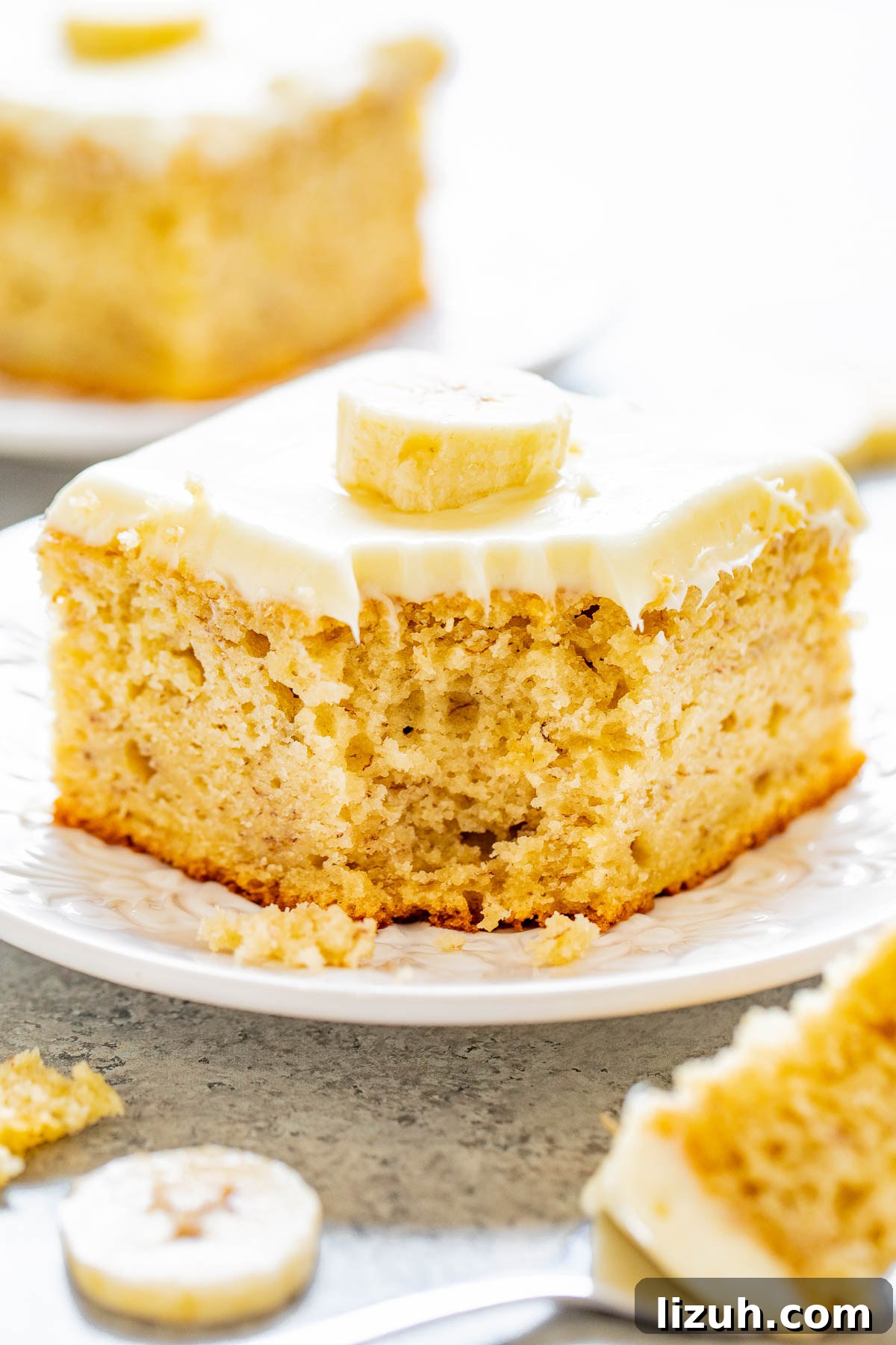 Best Banana Cake with Cream Cheese Frosting, a corner bite missing. 