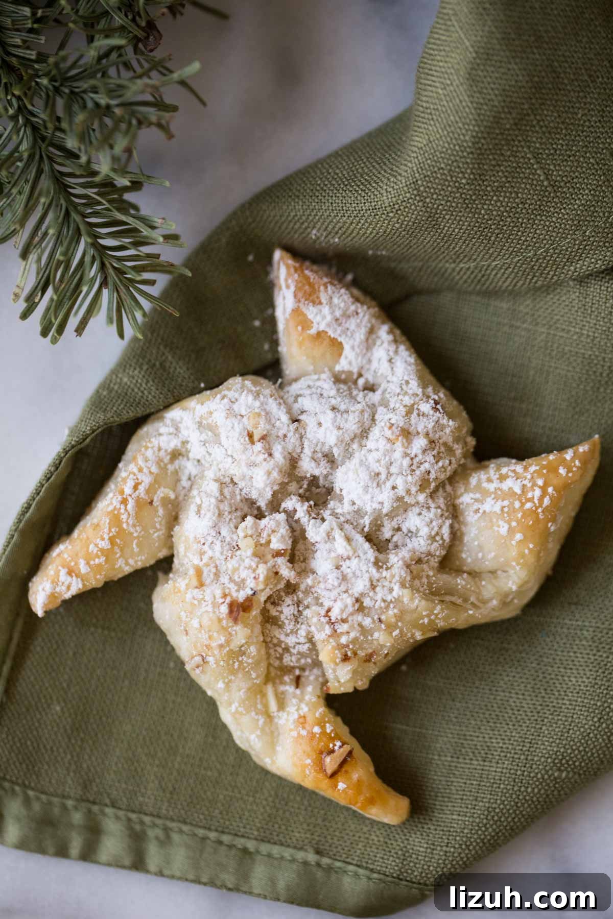 A Make Ahead Almond Pinwheel sitting on a green cloth napkin. 