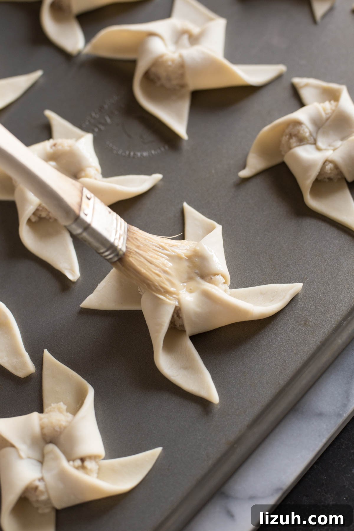 Make Ahead Almond Pinwheels on a baking sheet being brushed with the egg wash.   