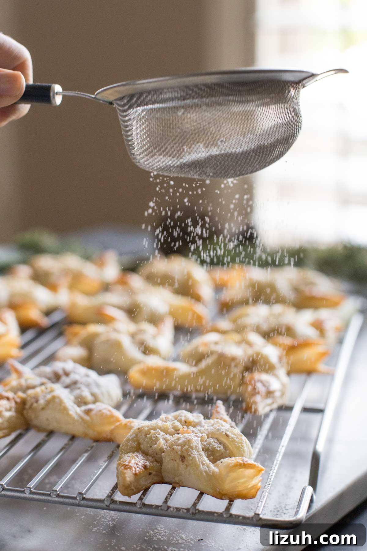Make Ahead Almond Pinwheels on a cooling rack, being sprinkled with powdered sugar. 